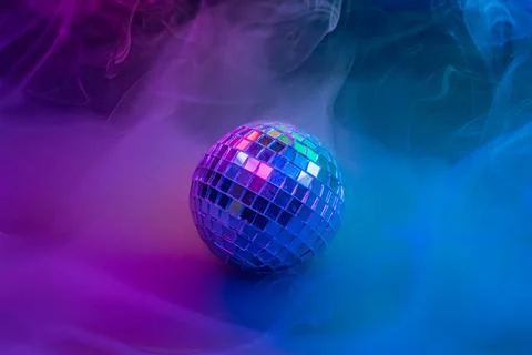 A dynamic stock image showcases a disco ball in colorful smoke, creating a .. Stock Photos