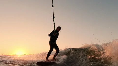 A Dynamic Sunset Surfing Experience: Capturing the Thrill and Joy of Riding Stock Footage 322537882