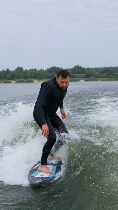 Dynamic Surfing Action on Calm Waters: A Surfer Balances Skillfully on a Stock Footage 322553728