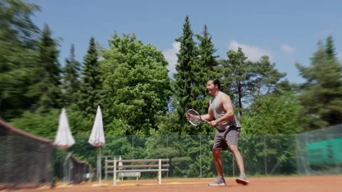 A Dynamic Tennis Player Engaged in Action on a Clay Court Within a Vibrant Stock Footage 310466093