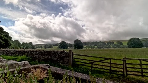 Dynamic timelapse showcasing rapidly moving clouds above a peaceful green Stock Footage 340877044