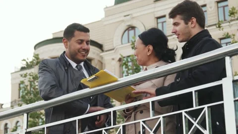 Dynamic trio engaged in a lively discussion over important documents in a folder Stock Footage 311944090