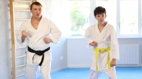 Dynamic underage boy performing fighting positions with middle-aged trainer Video stock 280952470
