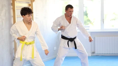 Dynamic underage boy performing fighting positions with middle-aged trainer Video stock 312627177