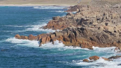 Dynamic video of ocean waves crashing against rugged rocky cliffs at Praia de Stock Footage 346692113