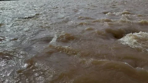 Dynamic view of turbulent muddy river water with swirling eddies and churni.. Stock Footage 339296483