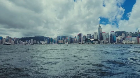 A dynamic view from the water captures the bustling Hong Kong skyline with Stock Footage 338311019