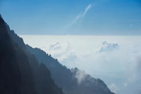A dynamic view of white clouds surrounding a granite mountain. Foto stock