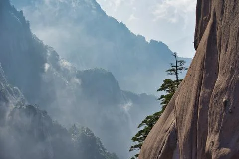 A dynamic view of white clouds surrounding a granite mountain. Stock Photos