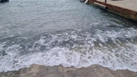 Dynamic waves hitting concrete pier with foamy coastal water motion Stock Footage 321651089