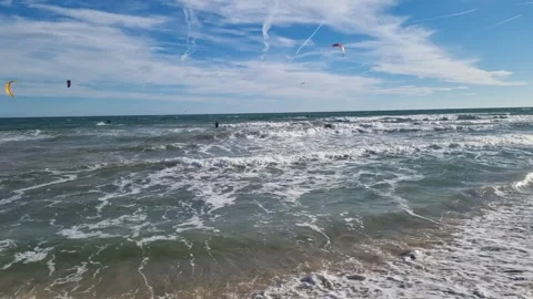 Dynamic windy beach scene with active kitesurfers riding powerful waves Video stock 321859447