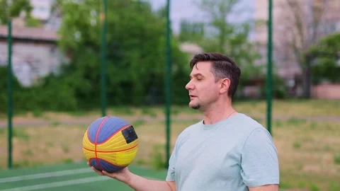 Dynamic young man dunking basketball at center of green court. Stock Footage 314311652