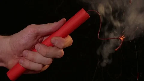 Dynamite in hand with a burning fuse on a black background Stock Footage 75382706