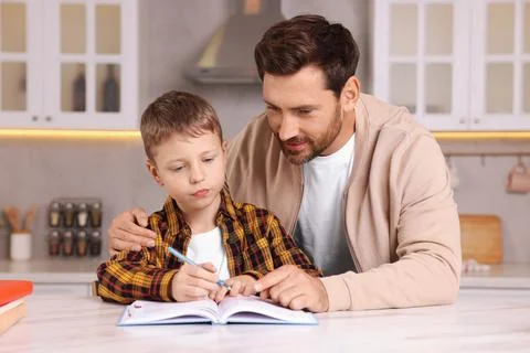 Dyslexia problem. Father helping son with homework at table in kitchen 스톡 사진