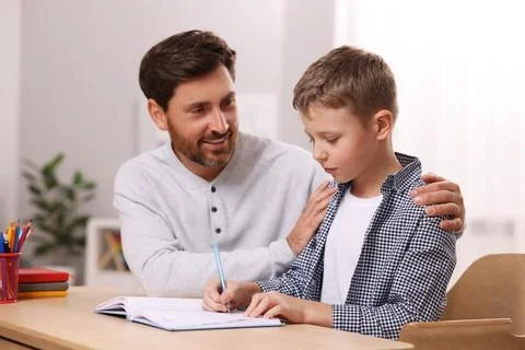 Dyslexia problem. Father helping son with homework at table in room Stock Photos