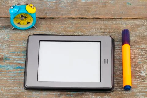 E-book reader and alarm on wooden table Stock Photos