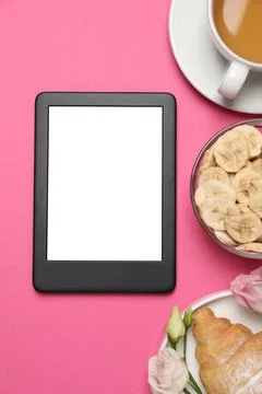 E-book reader with breakfast and flowers on pink background, flat lay. Space  Stock Photos