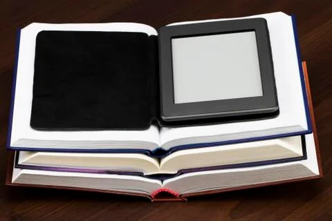 E-book reader device on desk in library. Alternative for traditional books Stock Photos