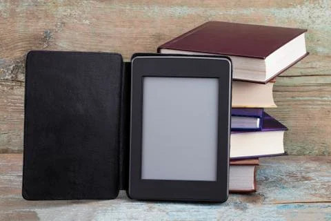 E-book reader device on desk in library. Alternative for traditional books Stock Photos