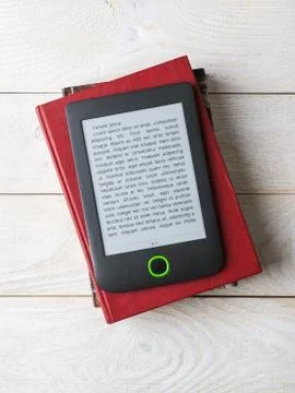 E-book reader on a stack of paper books over a white wooden table. Copy space Stock Photos