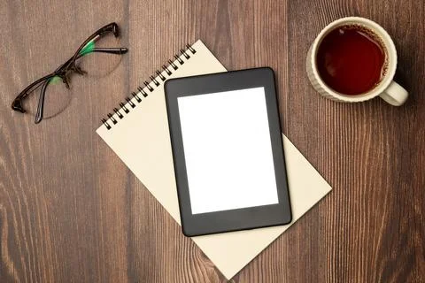 E-books, notebook, glasses and cup of tea on wooden background from above. Fl Stock Photos