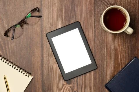 E-books, notebook, glasses and cup of tea on wooden background from above. Fl Stock Photos