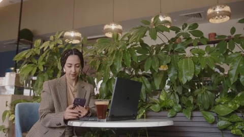 E-business entrepreneur multitasking working on smartphone and laptop at cafe Stock Footage 244602184