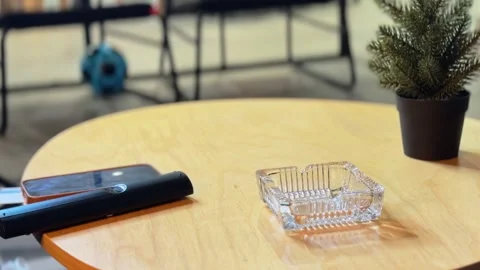 E-Cigarette And Glass Ashtray Remote Control And Smartphone On Wooden Table On Stock Footage 338426804