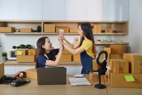 E-commerce Collaboration. Two women celebrating success in a modern workspace. Stock Photos
