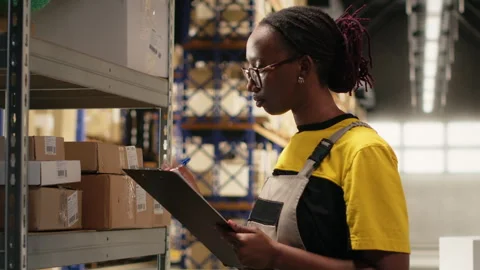 E-commerce female employee checking parcel details on clipboard 스톡 동영상 315709955