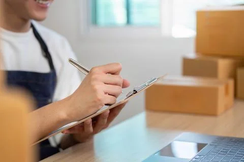 E-commerce professional managing orders with clipboard and laptop Stock Photos