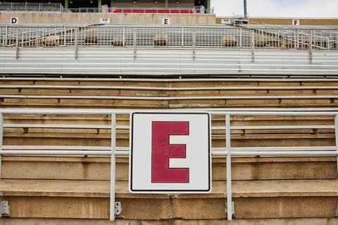 E, D, F sections of empty stands at sports stadium under gloomy sky on lettered Stock Photos