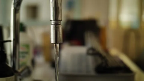 E Dolly shot out of focus cluttered kitchen to running tap 4K Stock Footage 240603632
