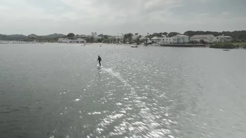 E-Foil Rider Gliding Across the Sea with Menorca Town in the Background Stock-Footage 344193340