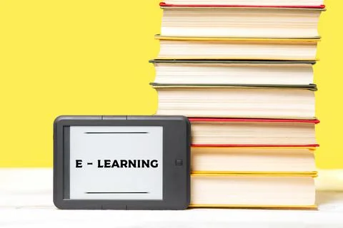 E-learning. E-book reader and a stack of books on a yellow background. Copy s Stock Photos