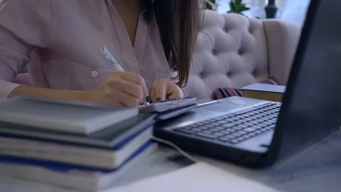 E-learning technology, student girl with pen writes notes in notebook sitting at Stock Footage 98924937