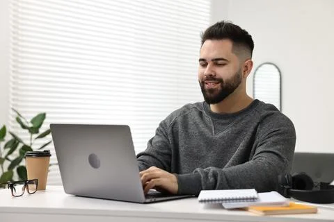 E-learning. Young man using laptop during online lesson at white table indoor Foto stock