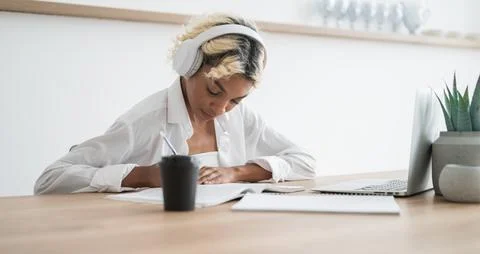 E-learning,online education concept.Happy student in headphones writing down Stock Photos