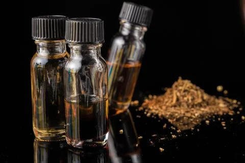 E-liquid bottles next to grinded tobacco leaves Foto stock