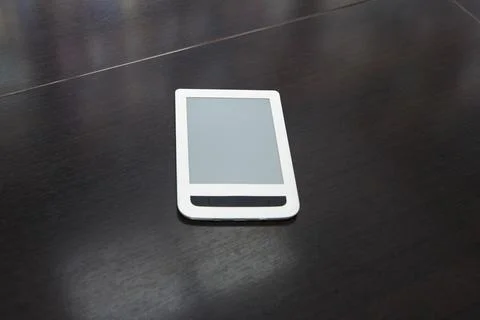 E-reader device placed on a dark wooden table surface in a minimal office set Stock Photos