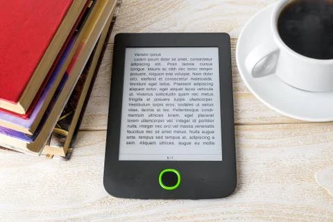E-reader, stack of ordinary paper books and cup of hot coffee on a wooden table Stock Photos