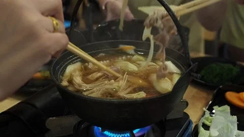 Each members of dining table used chopsticks to grab food from a Shabu Shabu pot Stock Footage 144976510
