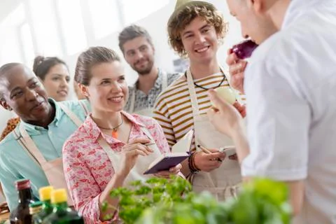 Eager students taking notes and listening to chef teacher in cooking class Stock Photos