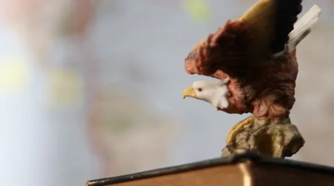 Eagle carving in front of world map. Rack-focus, pan, and tilt to eagle.1080p24. Stock Footage 22726194