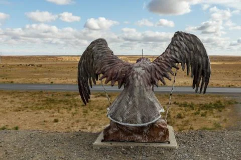 Eagle statue with spread wings on the mountain against the sky in the steppe Stock Photos