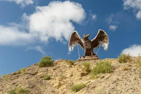 Eagle statue with spread wings on the mountain against the sky in the steppe Stock Photos