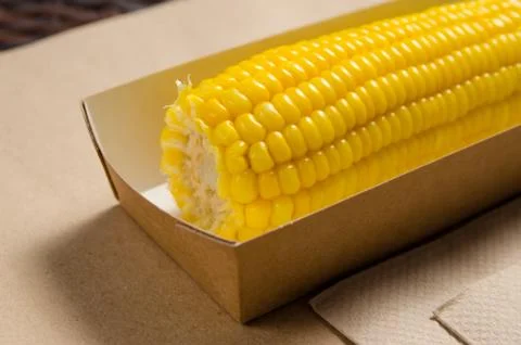 An ear of boiled corn in an eco-friendly cardboard box Stock Photos