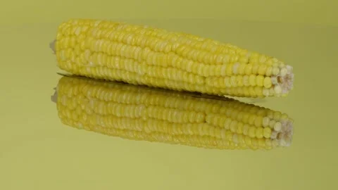 An ear of boiled corn on yellow mirror. Extrem close-up. Stock Footage 162950432