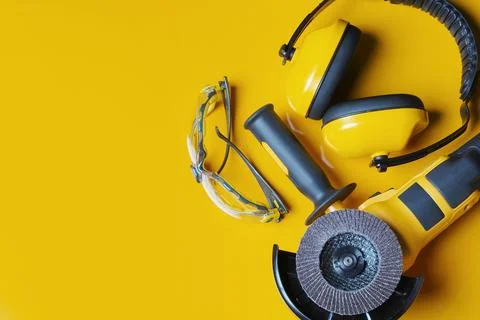 Ear Muffs, Angle Grinder and Safety glasses on yellow background .Work safe.. Stock Photos