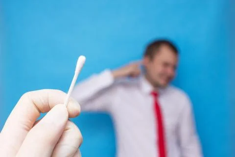 Ear plug in the ear of a young man, the doctor holds in his hand a remedy for Foto stock